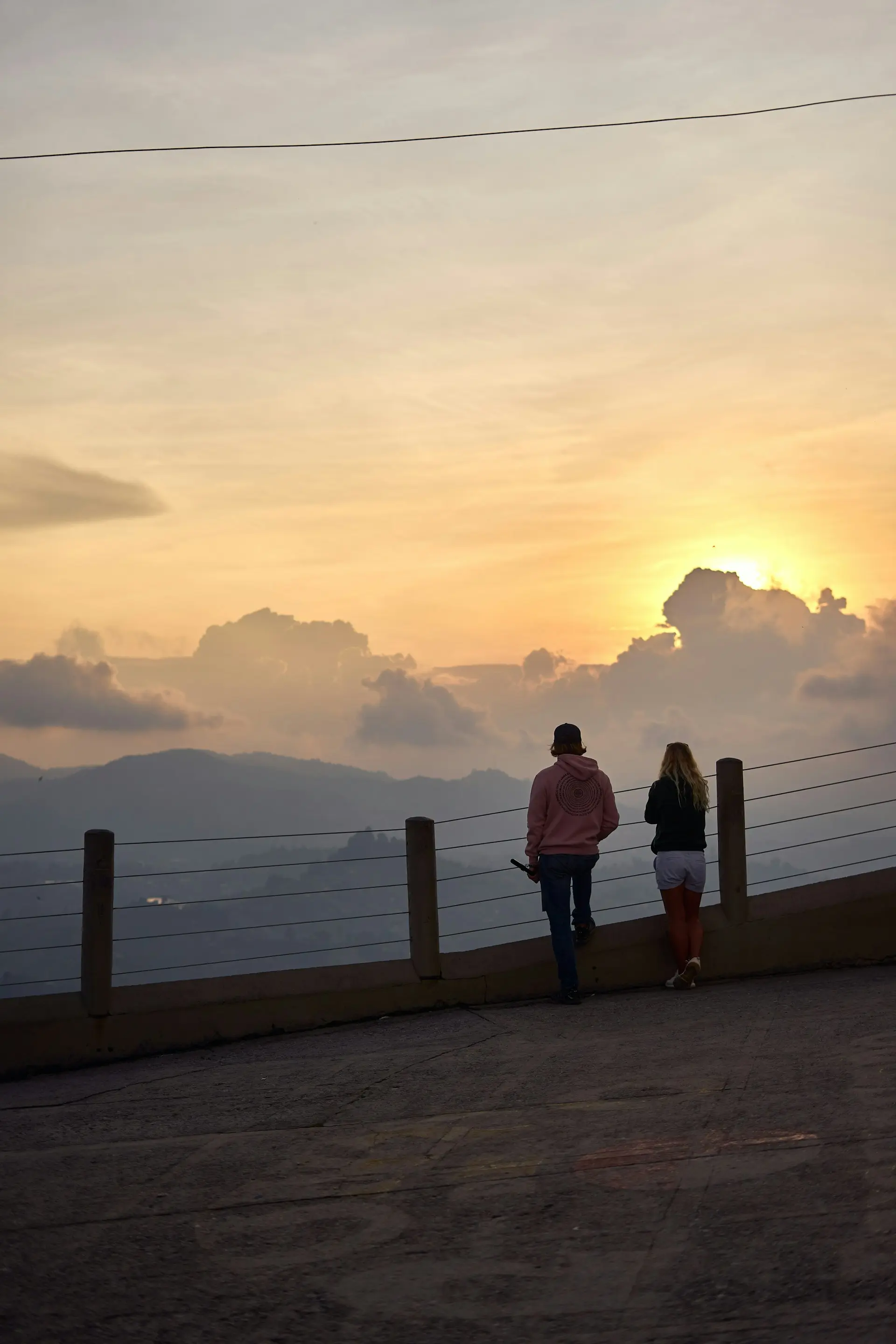 Couple at a mountain viewpoint under a golden sunset sky
