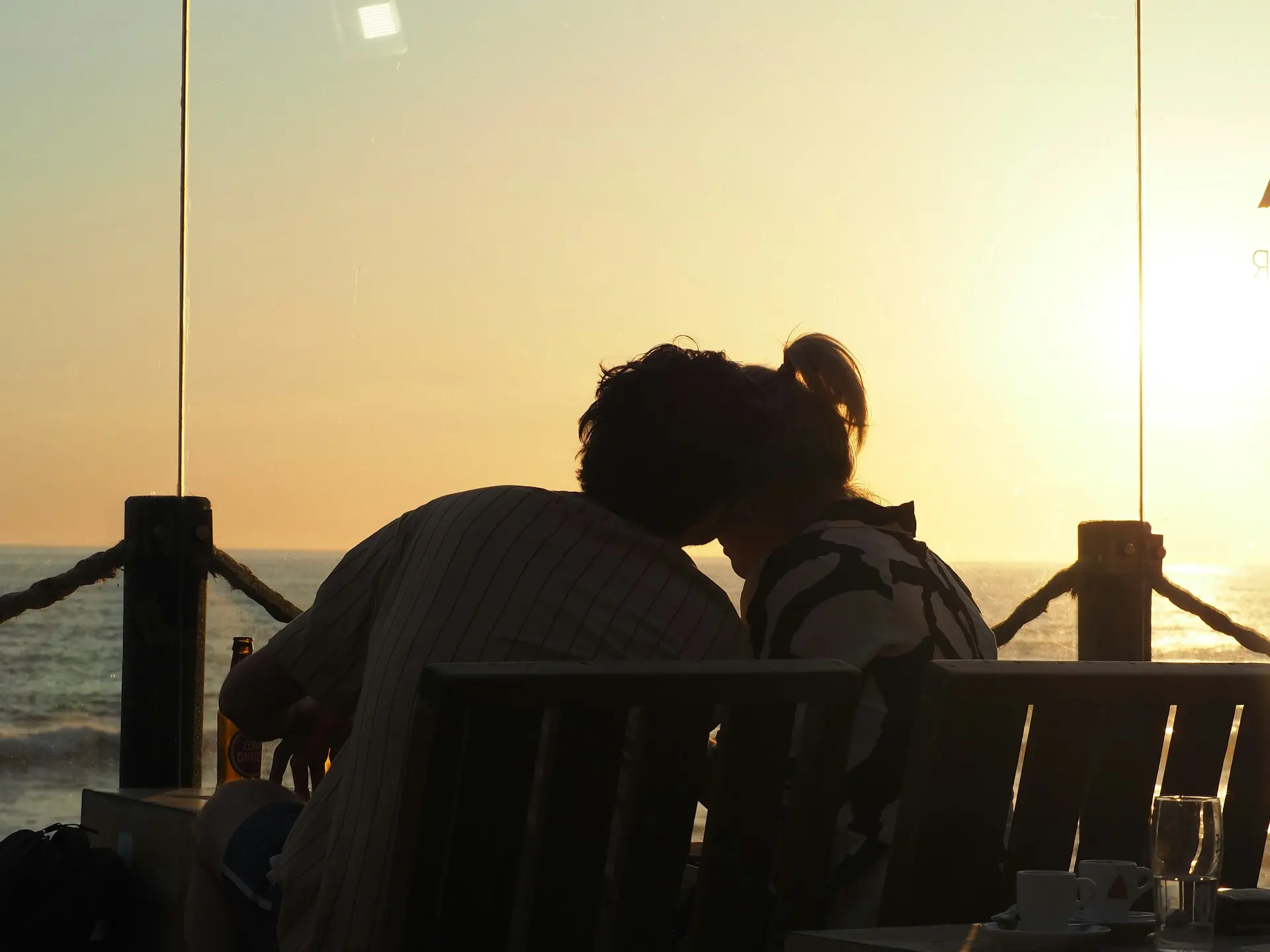 Couple silhouette at a coastal bar during golden hour